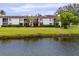 A backyard view showing a condo with a screened in back porch on a well maintained green lawn by the water at 129 Lakeview Way, Oldsmar, FL 34677
