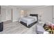 A modern bedroom with light gray walls, wood flooring, and a gray bed with white linens at 129 Lakeview Way, Oldsmar, FL 34677