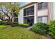 Exterior view of a two story condo with a screened in porch surrounded by mature landscaping and green grass at 129 Lakeview Way, Oldsmar, FL 34677