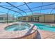 Screened in pool and spa features brick pavers and a tranquil water feature in a lush backyard setting at 1408 Brilliant Cut Way, Valrico, FL 33594