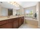 Primary bathroom featuring double sinks, soaking tub, walk-in shower, and plenty of natural light at 18243 Cypress Bay Pkwy, Land O Lakes, FL 34638