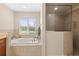 Bright bathroom featuring a soaking tub, glass shower, and window providing ample natural light at 18243 Cypress Bay Pkwy, Land O Lakes, FL 34638