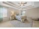 Bright bedroom featuring tray ceilings, a ceiling fan, and a large window with natural light at 18243 Cypress Bay Pkwy, Land O Lakes, FL 34638