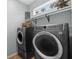 Laundry room features modern washer and dryer with shelving and a small window at 18243 Cypress Bay Pkwy, Land O Lakes, FL 34638