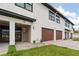 Modern townhouse exterior featuring a wood-look garage door and stone entryway at 187 145Th E Ave # 3, Madeira Beach, FL 33708