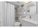 Bright bathroom features a shower-tub, white vanity, and a decorative round mirror at 19029 Us Highway 19 N # 26-204, Clearwater, FL 33764