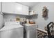 Compact laundry area with a washer, dryer, overhead cabinets, and storage shelf at 19029 Us Highway 19 N # 26-204, Clearwater, FL 33764