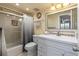 Well-lit bathroom with a single sink vanity, framed mirror, and tiled shower with glass door at 19029 Us Highway 19 N # 9-407, Clearwater, FL 33764