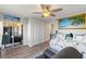 Bedroom featuring wood floors, a ceiling fan, a sliding glass door, and a beach painting at 19029 Us Highway 19 N # 9-407, Clearwater, FL 33764