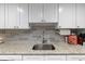 Bright kitchen featuring a stainless steel sink, granite countertops, and gray backsplash at 19029 Us Highway 19 N # 9-407, Clearwater, FL 33764