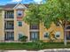Inviting yellow building with multiple balconies, lush landscaping, and a wrought iron fence at 1910 E Palm Ave # 11216, Tampa, FL 33605