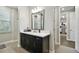 Stylish bathroom with a dark wood vanity, quartz countertops, framed mirror, and a view of the walk-in closet at 19719 Cypress Bridge Dr, Odessa, FL 33556