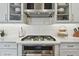 Modern kitchen featuring a stainless steel cooktop, range hood, and white cabinets with a stylish backsplash at 19719 Cypress Bridge Dr, Odessa, FL 33556