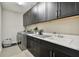 Laundry room featuring stainless steel appliances, dark cabinets, and tile flooring at 19719 Cypress Bridge Dr, Odessa, FL 33556