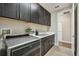 Laundry room with stainless steel appliances, dark cabinets, and white countertops at 19719 Cypress Bridge Dr, Odessa, FL 33556