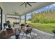 This covered patio has neutral toned furniture and a view of the backyard and trees beyond at 19719 Cypress Bridge Dr, Odessa, FL 33556