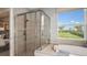 Bright bathroom with a soaking tub, glass shower, and a large window offering serene views of the outdoors at 3408 Lumber Falls Dr, Plant City, FL 33565