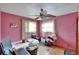 Cozy bedroom featuring pink walls, hardwood floors, and natural light from two windows at 4102 Haines N Rd, St Petersburg, FL 33703