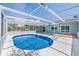 Screened-in pool with bright blue water, surrounded by a patio and lush landscaping at 4307 Woodfield Ave, Holiday, FL 34691