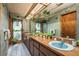Eclectic bathroom features a long vanity with blue sinks, wood cabinets, and skylight at 50 Pembrook Cir, Palm Harbor, FL 34683