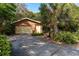 Charming single-story home featuring a two-car garage, a mature palm tree, and lush landscaping at 50 Pembrook Cir, Palm Harbor, FL 34683