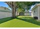 Spacious backyard with lush green grass, a large tree, white fence and storage shed at 5302 S Himes Ave, Tampa, FL 33611