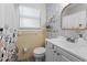 Bathroom featuring stylish floral wallpaper, a decorative mirror, and updated fixtures at 5302 S Himes Ave, Tampa, FL 33611