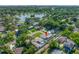 An aerial shot shows a home with a pool and screened-in patio, surrounded by lush greenery and a serene lake at 6345 Dartmouth N Ave, St Petersburg, FL 33710