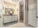 Well-lit bathroom with double sink vanity, large mirror, and a tiled walk-in shower at 6477 Dutton Dr, Wesley Chapel, FL 33545