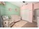 Pastel Bedroom with decorative accent wall, crib and a comfortable rocking chair at 6477 Dutton Dr, Wesley Chapel, FL 33545