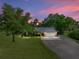 Charming home with a metal roof, lush lawn and mature trees under a beautiful sunset sky at 7508 W Short Rd, Plant City, FL 33565