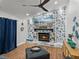 Cozy living room featuring stone fireplace, mounted TV, wood floors, and a comfortable ottoman for relaxing at 7508 W Short Rd, Plant City, FL 33565