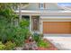 Close up view of the house, showing front door, front-facing garage and lush tropical landscaping at 7615 S Fitzgerald St, Tampa, FL 33616