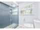 Beautiful bathroom featuring a blue-tiled shower with glass doors and a window offering natural light at 8238 30Th N Ave, St Petersburg, FL 33710