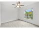 Bright bedroom with a ceiling fan and a window with a view of tropical landscaping at 8598 Parsons Hill Blvd, Wesley Chapel, FL 33545