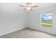 Bedroom with neutral carpet, white walls, a ceiling fan, and a window offering a pleasant view at 8598 Parsons Hill Blvd, Wesley Chapel, FL 33545