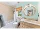 Bright bathroom features a marble vanity, decorative mirror, tub with shower, and natural light from the window at 90 Bahama Cir, Tampa, FL 33606