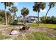 Spacious backyard with lush palm trees, manicured lawn and cozy fire pit perfect for relaxing outdoors at 9048 Wharf Ave, Placida, FL 33946