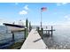 Dock with American flag and boat lift underneath a blue sky with scattered puffy white clouds at 9048 Wharf Ave, Placida, FL 33946