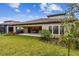 Exterior featuring covered patio, landscaped garden, well-maintained lawn, and screened-in pool at 11146 Rustic Timber Loop, San Antonio, FL 33576