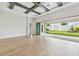 Open-concept living room with light wood flooring, a coffered ceiling, and sliding glass doors leading to the backyard at 11146 Rustic Timber Loop, San Antonio, FL 33576