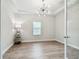 A modern office with wood floors features a modern chandelier and large window providing plenty of light at 11146 Rustic Timber Loop, San Antonio, FL 33576
