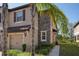 Charming townhouse featuring a beige facade with brick accents, a single-car garage, and lush landscaping at 11704 Castine St, New Port Richey, FL 34654