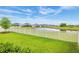 Landscaped backyard with a white picket fence overlooking a tranquil pond and neighboring homes at 12916 Brookside Moss Dr, Riverview, FL 33579