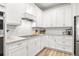 Close-up of the kitchen featuring white cabinets, stainless steel appliances, and white subway tile backsplash at 12916 Brookside Moss Dr, Riverview, FL 33579