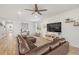 Bright, open-concept living room with wood-look flooring, stylish decor, and a large brown leather sectional sofa at 12916 Brookside Moss Dr, Riverview, FL 33579