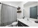 Clean bathroom with a single sink vanity, toilet, shower with curtain and decorative shelves at 14100 Holly Hammock Ln, Brooksville, FL 34613