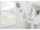 Bright bathroom features a round mirror, pedestal sink, and charming decorative accents at 14100 Holly Hammock Ln, Brooksville, FL 34613