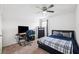 Comfortable bedroom setup with carpet flooring, window, desk, and blue bed covers at 14100 Holly Hammock Ln, Brooksville, FL 34613