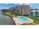 Aerial view of community pool, sun loungers and manicured grounds with water views at 1847 Shore S Dr # 204, South Pasadena, FL 33707